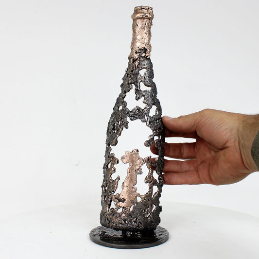 Sculpture de Philippe Buil représentant une bouteille de champagne en dentelle de métal : acier et bronze
