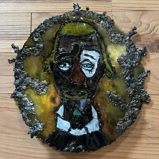 Sculpture murale en acier réalisée par Philippe Buil, représentant un visage de clown inspiré de Bernard Buffet, avec dentelle de métal et pigments colorés.