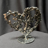 Sculpture de cœur en dentelle de métal noir et bronze par Philippe Buil, vue de dos sur socle circulaire.