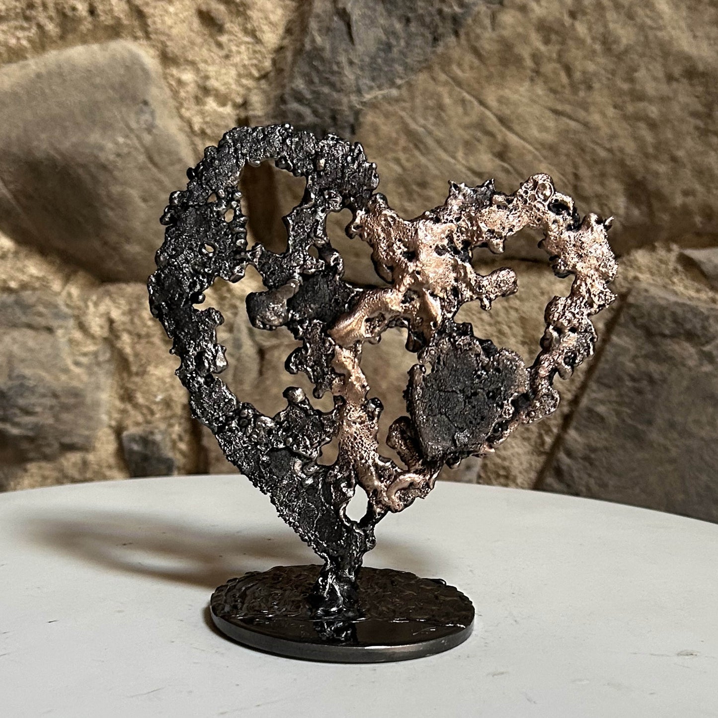Sculpture de cœur en dentelle de métal noir et bronze par Philippe Buil, en situation