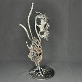 Sculpture en dentelle de métal représentant une tête de mort associée à une coquille Saint-Jacques, réalisée en acier et bronze par Philippe Buil.