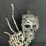 Sculpture en dentelle de métal représentant une tête de mort associée à une coquille Saint-Jacques, réalisée en acier et bronze par Philippe Buil.