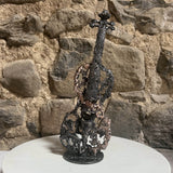 Philippe Buil, sculpteur ontemporain présente un violon en dentelle de métal acier et bronze sur un mur en pierre