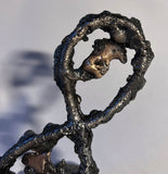 Cette sculpture de Philippe Buil, réalisée en dentelle de métal (acier et bronze), représente le symbole de l'infini. Ce symbole mathématique, en forme de huit couché, évoque l'idée d'une continuité sans fin, d'un cycle perpétuel, d'un renouveau constant.