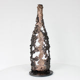 Sculpture de Philippe Buil représentant une bouteille de champagne en dentelle de métal : acier et bronze