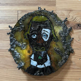 Sculpture murale en acier réalisée par Philippe Buil, représentant un visage de clown inspiré de Bernard Buffet, avec dentelle de métal et pigments colorés.