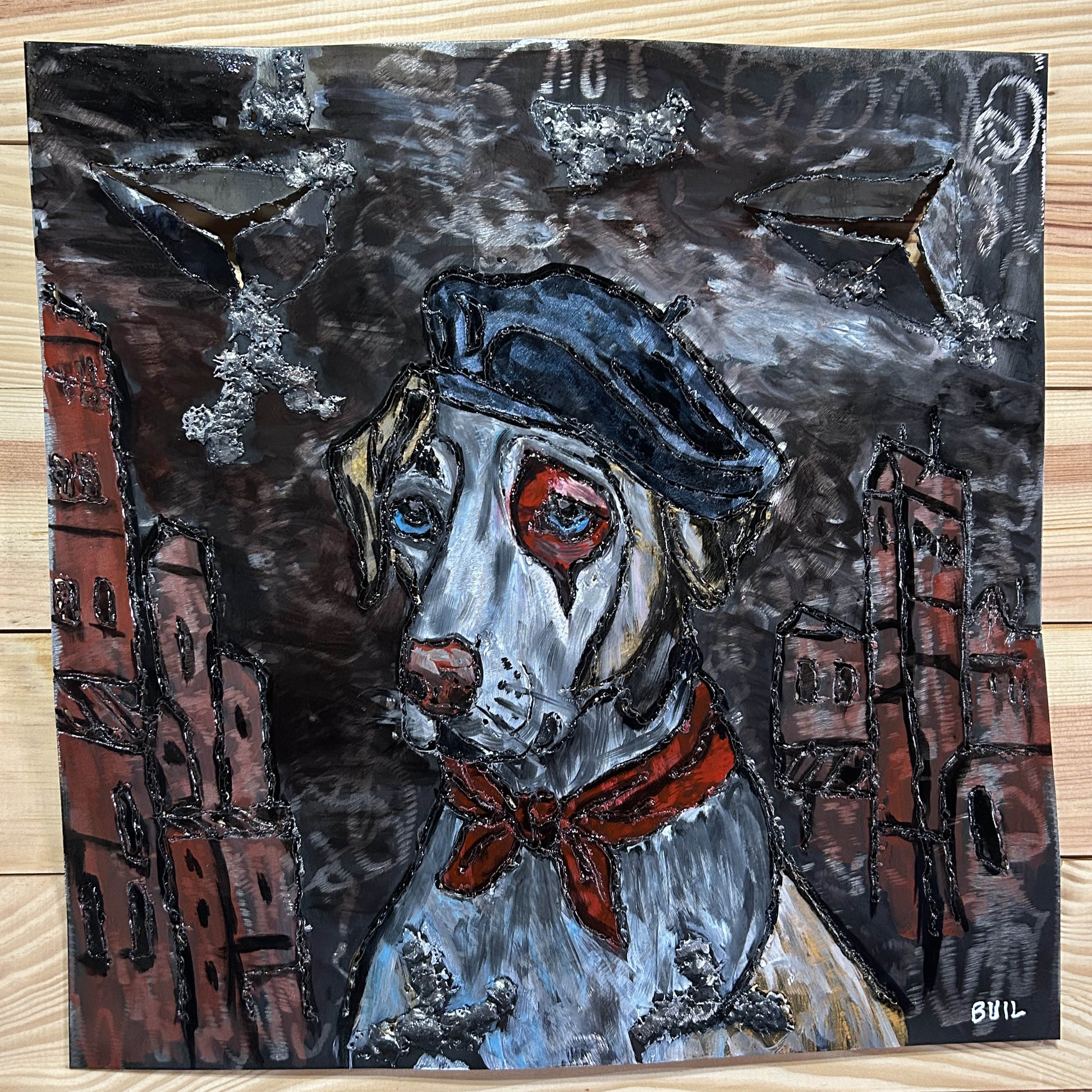 Sculpture murale en métal de Philippe Buil représentant un chien portant un béret et un foulard basque, avec pigments colorés et fond texturé sombre