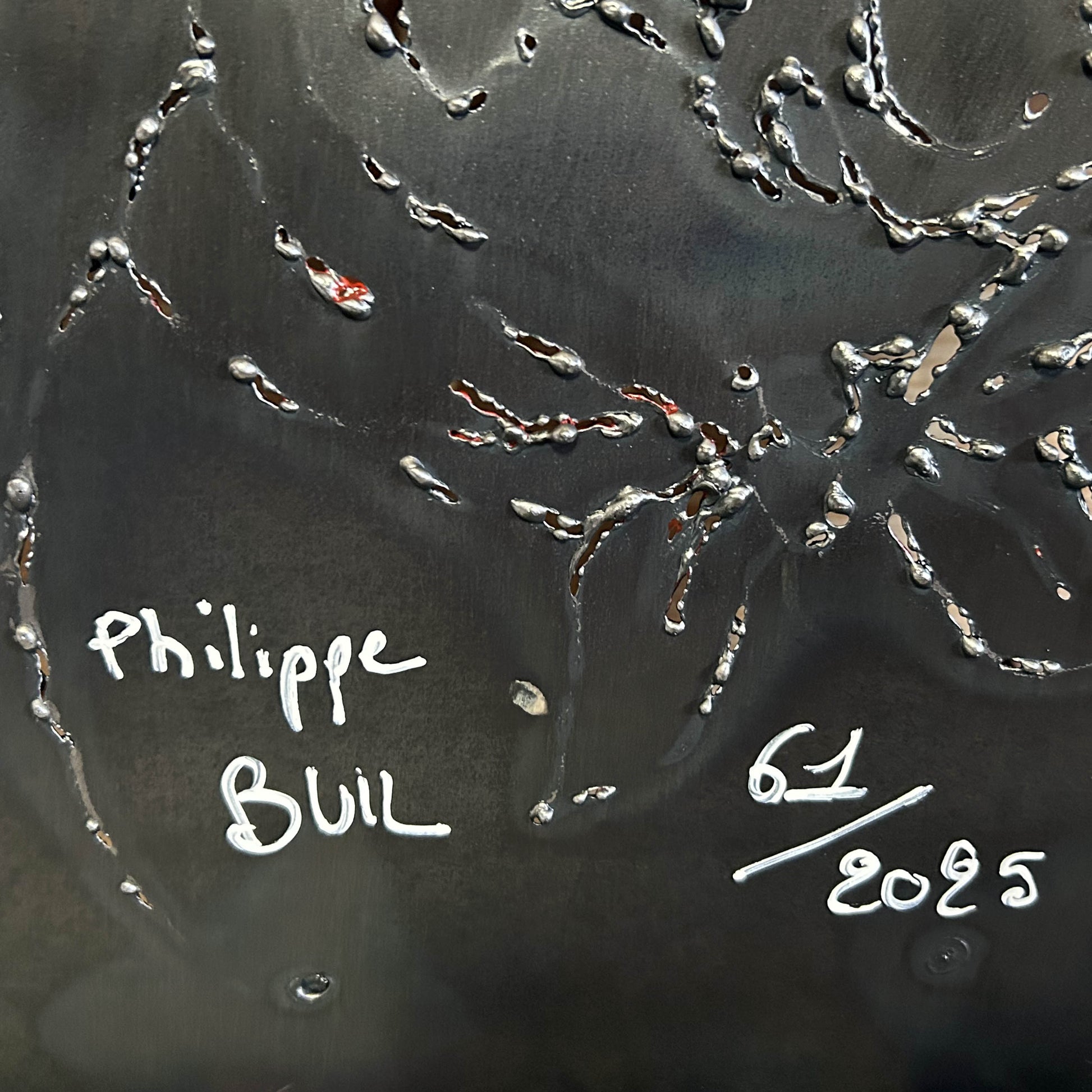 Sculpture murale en métal de Philippe Buil représentant un chien portant un béret et un foulard basque, avec pigments colorés et fond texturé sombre