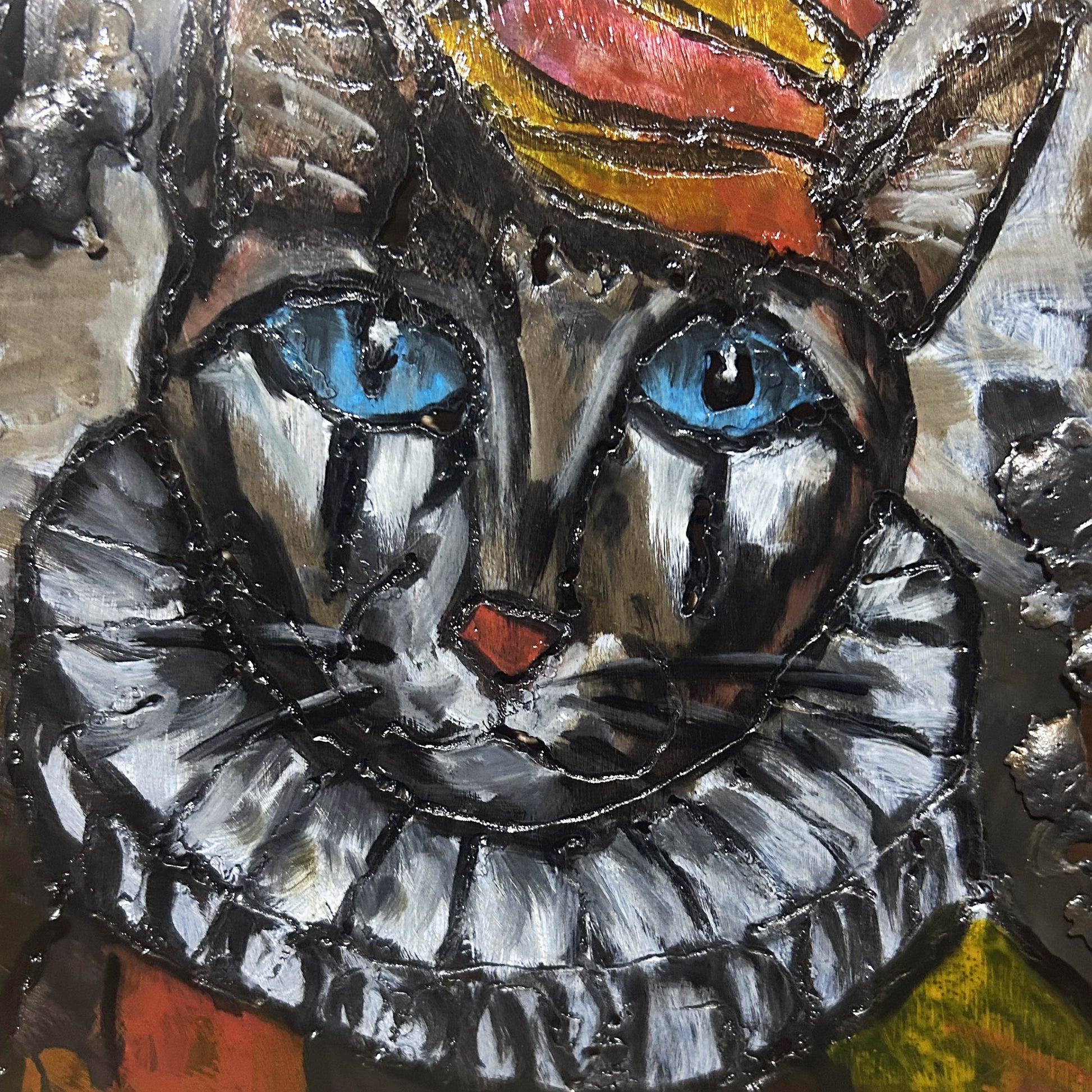 Sculpture murale carrée de 25x25 cm représentant un chat arlequin aux yeux bleus intenses, portant une collerette blanche et un chapeau rayé rouge et jaune. L’œuvre est réalisée en acier texturé et pigments, avec un fond gris brumeux et métallisé