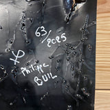 Tableau mural de 25×25 cm représentant un chat à béret dans un décor urbain gris et texturé. L’œuvre est réalisée en métal découpé avec des zones de dentelle de métal et colorée avec des pigments, créant un effet expressif et contrasté.