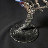 Sculpture de Philippe Buil représentant un visage humain en dentelle d'acier et bronze. Le côté gauche du visage est coloré avec des pigments bleus et rouges, tandis que le côté droit se transforme en une structure métallique ajourée et arborescente.