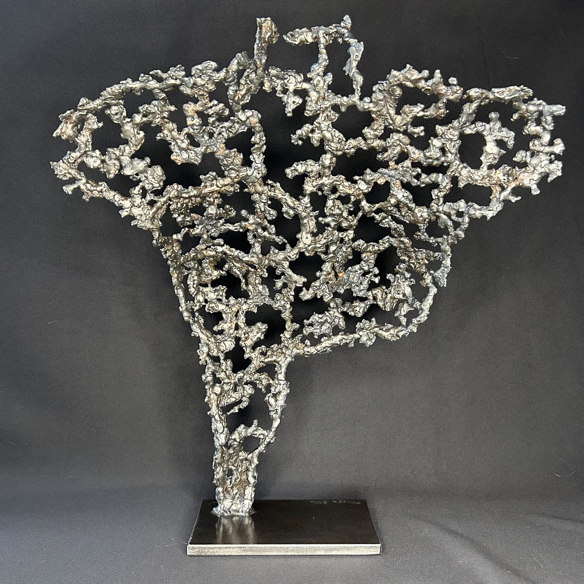 Sculpture contemporaine Belisama Le Souffle de Philippe Buil, buste de femme à taille réelle en dentelle de métal acier et bronze avec étoiles fondues, vue de dos sur fond sombre.