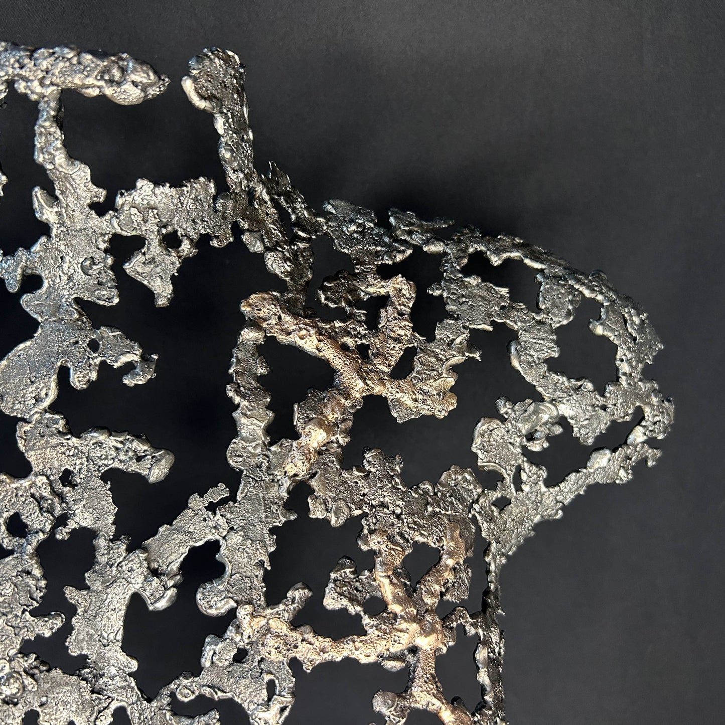 Détail Sculpture contemporaine Belisama Le Souffle de Philippe Buil, buste de femme à taille réelle en dentelle de métal acier et bronze avec étoiles fondues,  sur fond sombre.